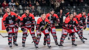 Équipe de hockey des Boxers de Bordeaux, souriante et fière sur la glace. Maillots rouges et noirs avec sponsors Voltéa, Bauer, Carrefour.